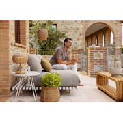 sticks platform sofa w/ chaise lounge Sand aluminium Light brown Cane-line Rise cushion in a patio with outdoor furniture and a man enjoying the sofa lifestyle