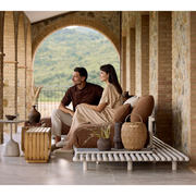 sticks platform corner sofa Sand aluminium Umber brown Cane-line Rise cushion in a patio with outdoor furniture and 2 people enjoying the sofa lifestyle