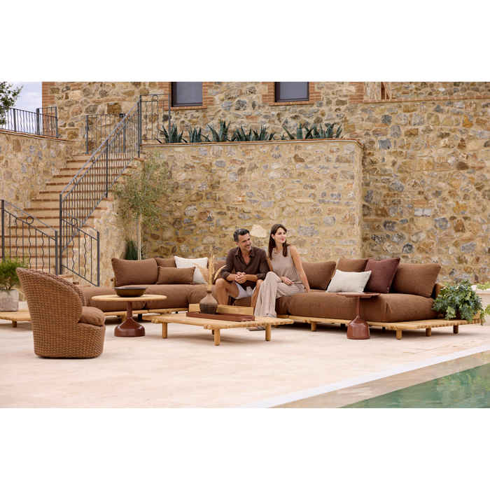 sticks platform corner sofa Teak Umber brown Cane-line Rise cushion in a patio with outdoor furniture and 2 people enjoying the sofa lifestyle