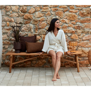 cane-line Sticks bench teak in a patio with a woman enjoying the bench lifestyle