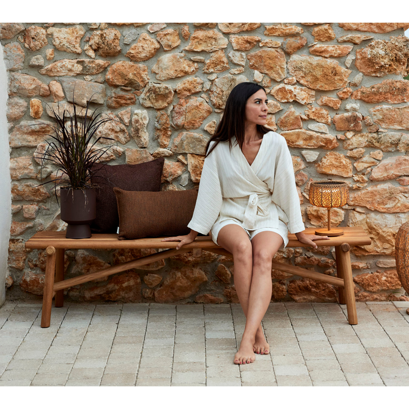 cane-line Sticks bench teak in a patio with a woman enjoying the bench lifestyle